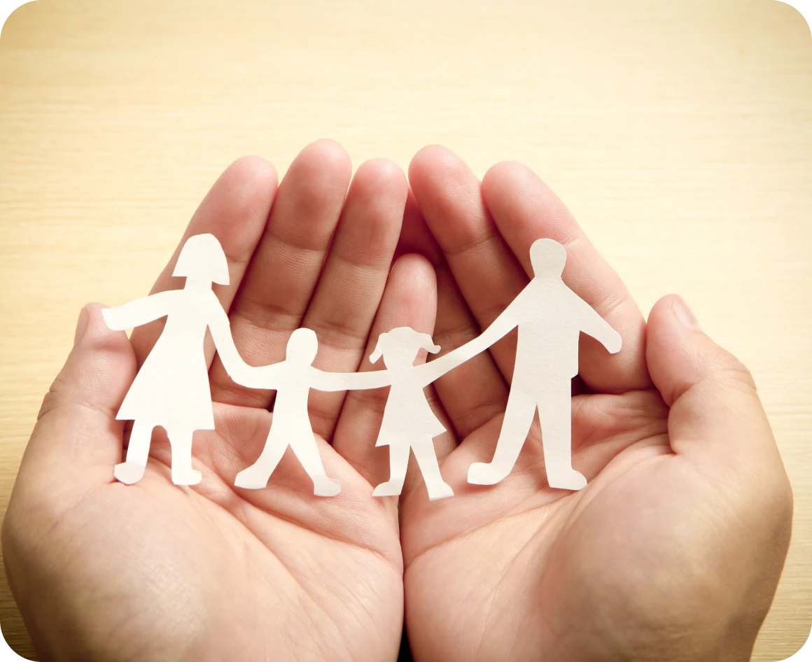 Hands holding paper family figures